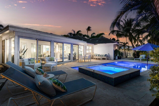 pool at dusk featuring an in ground hot tub and a patio area