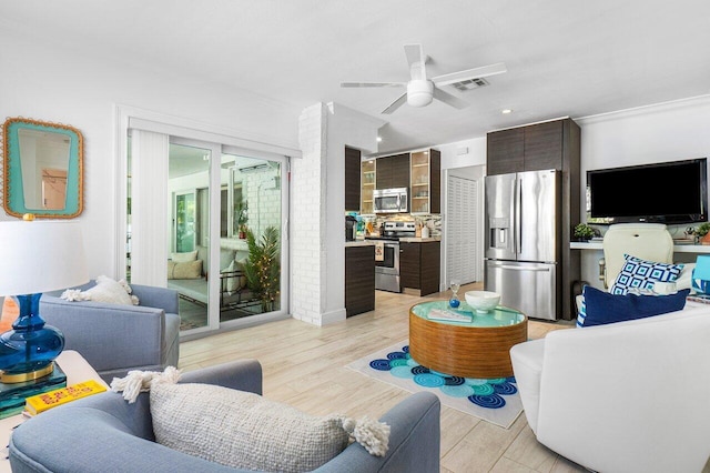 living room featuring ceiling fan, crown molding, and light hardwood / wood-style flooring