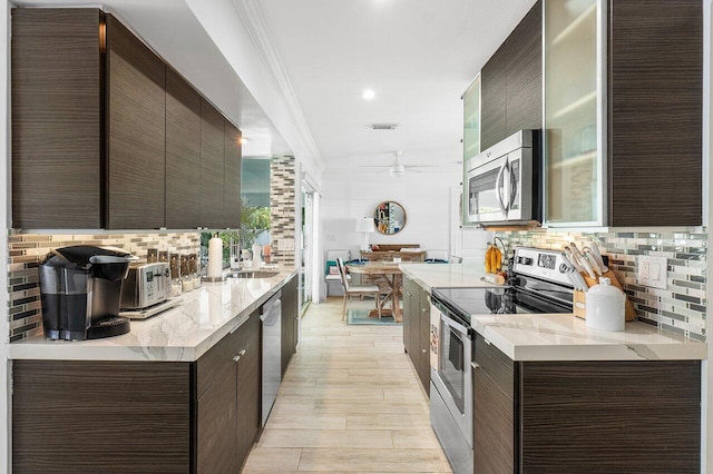 kitchen with decorative backsplash, light hardwood / wood-style flooring, ornamental molding, and appliances with stainless steel finishes