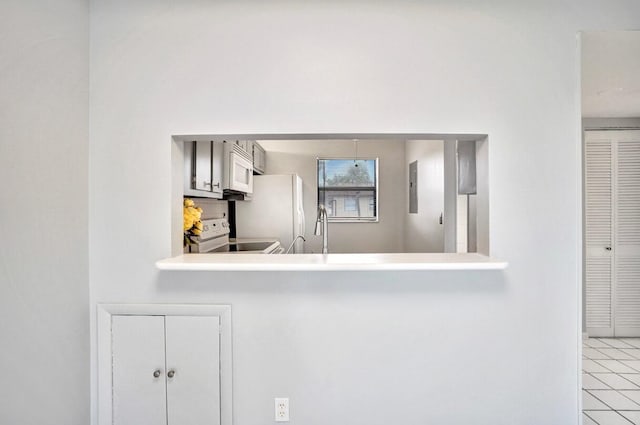 kitchen featuring electric panel, white appliances, kitchen peninsula, and light tile patterned floors