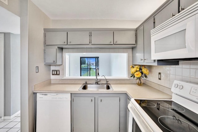 kitchen with light tile patterned floors, white appliances, gray cabinets, and sink