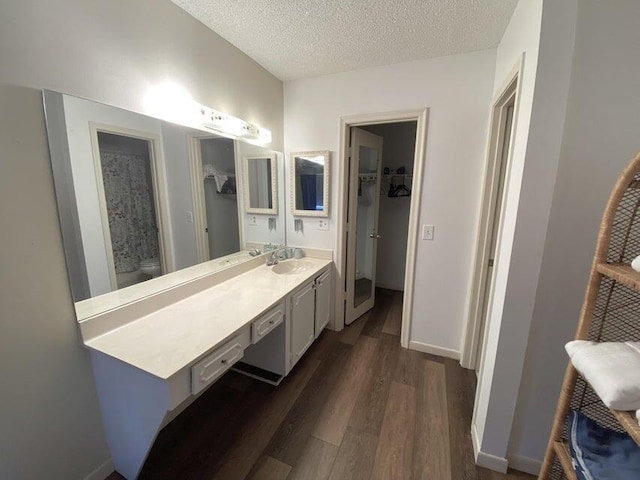 bathroom with vanity, wood-type flooring, a textured ceiling, and toilet