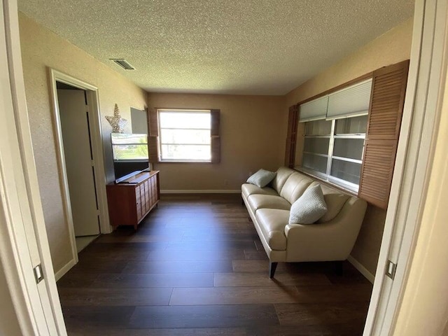 living room with a textured ceiling and dark wood-type flooring