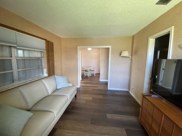 living room featuring dark wood-type flooring and a textured ceiling