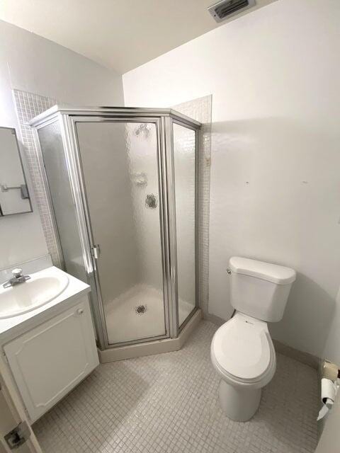 bathroom with tile patterned floors, vanity, toilet, and an enclosed shower