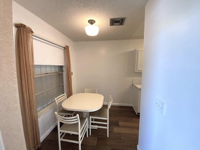 dining area with a textured ceiling and dark wood-type flooring