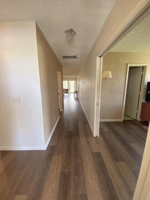 corridor featuring a textured ceiling and dark hardwood / wood-style floors