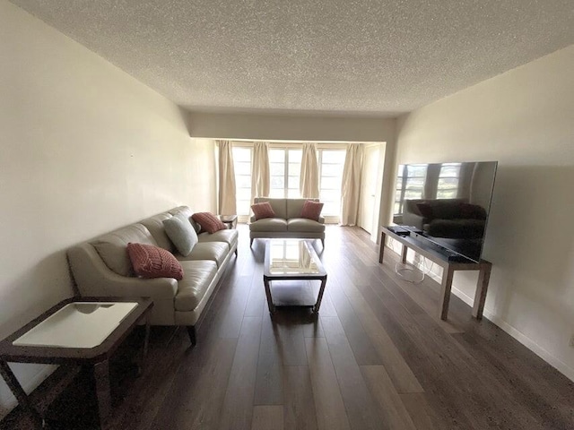 living room with a textured ceiling and dark wood-type flooring