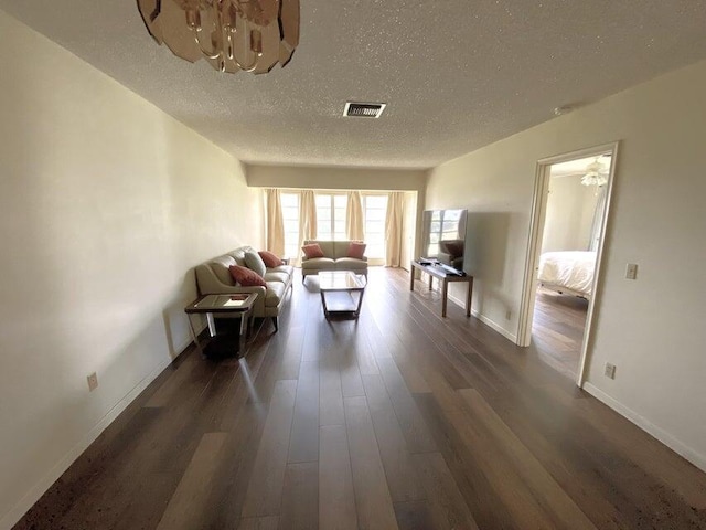 unfurnished living room featuring a textured ceiling, a notable chandelier, and dark wood-type flooring