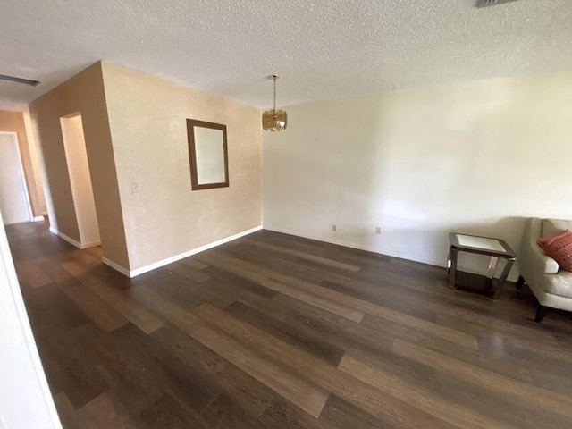 empty room with a textured ceiling and dark hardwood / wood-style flooring