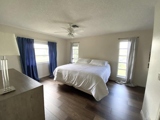 bedroom featuring ceiling fan, dark hardwood / wood-style flooring, a textured ceiling, and multiple windows