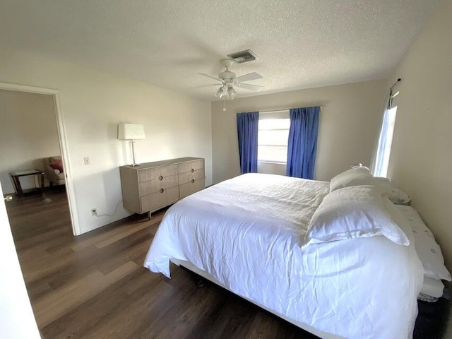 bedroom with ceiling fan, dark hardwood / wood-style flooring, and a textured ceiling