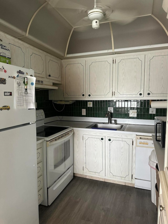 kitchen with sink, backsplash, white appliances, vaulted ceiling, and dark hardwood / wood-style flooring