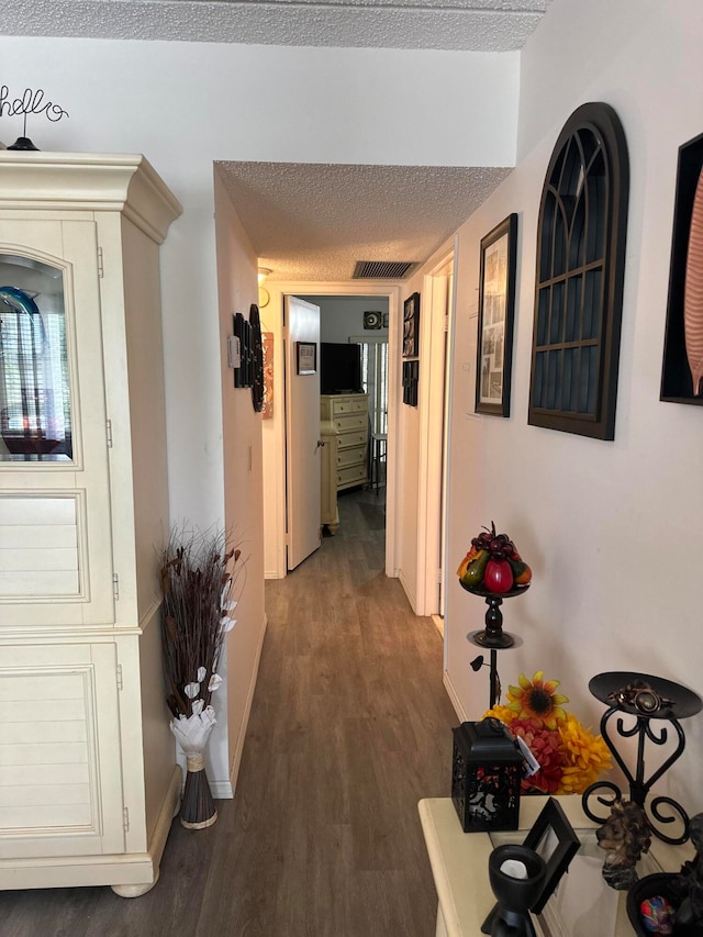 hallway featuring a textured ceiling and dark hardwood / wood-style floors