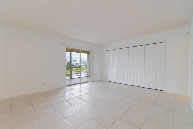 unfurnished bedroom featuring a textured ceiling, access to outside, and light tile patterned floors