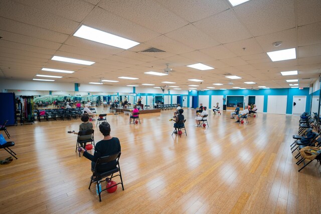 exercise room featuring light wood-type flooring and a drop ceiling