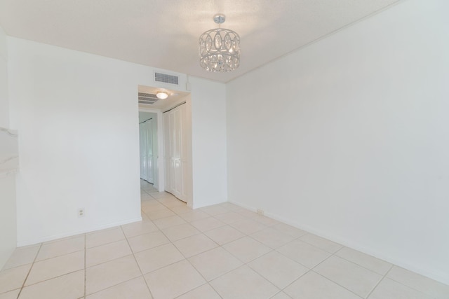 tiled empty room featuring a notable chandelier