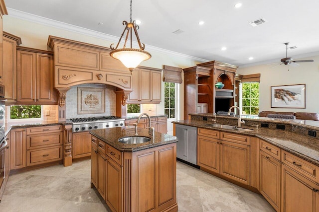 kitchen with hanging light fixtures, sink, dark stone countertops, and an island with sink