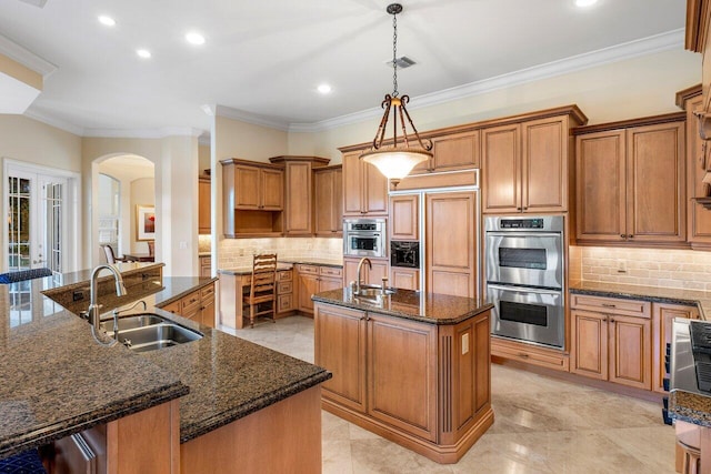 kitchen featuring pendant lighting, sink, crown molding, and an island with sink