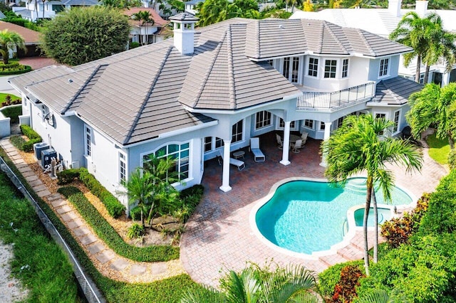 back of house featuring cooling unit, a fenced in pool, a patio area, and a balcony