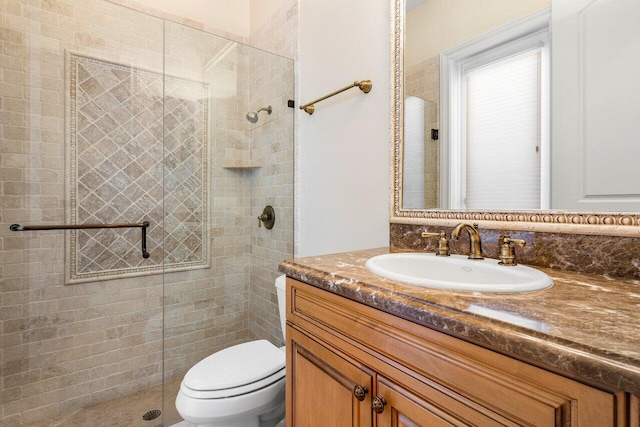 bathroom featuring vanity, toilet, and tiled shower