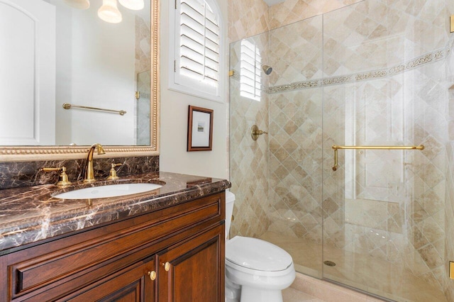 bathroom featuring toilet, vanity, and a shower with shower door