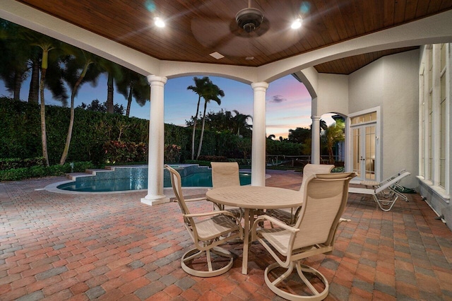 patio terrace at dusk featuring french doors, ceiling fan, and a fenced in pool