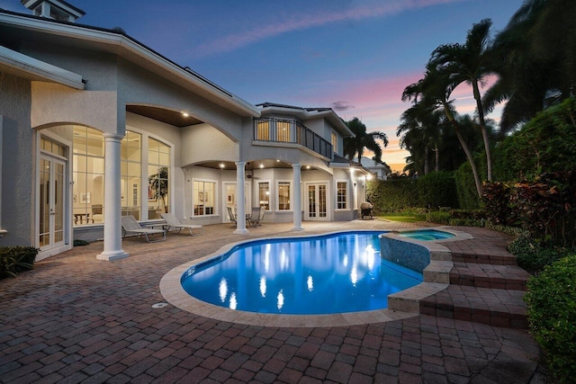 pool at dusk with a patio area and french doors