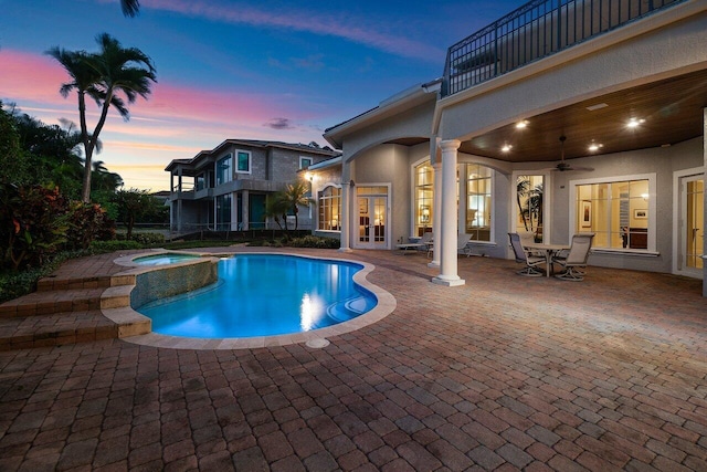 pool at dusk with a patio, ceiling fan, and an in ground hot tub