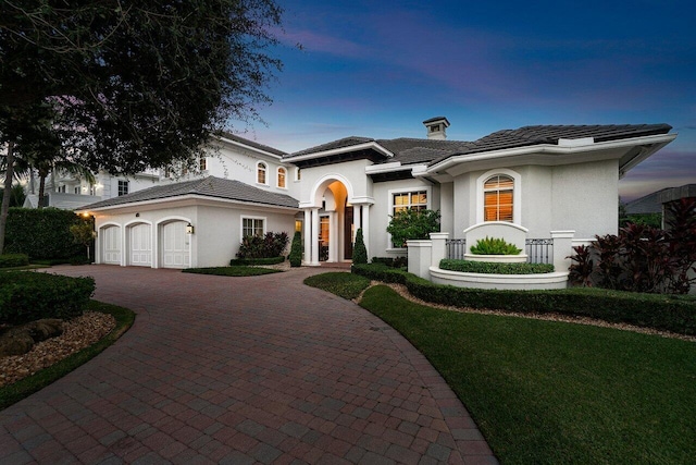 mediterranean / spanish-style home featuring a garage and a yard