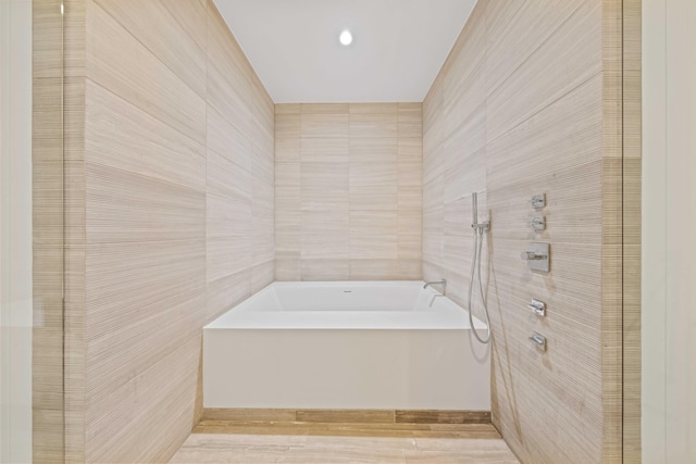 bathroom featuring a washtub, tile walls, and hardwood / wood-style flooring