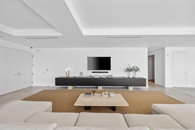 living room with a tray ceiling and light hardwood / wood-style flooring