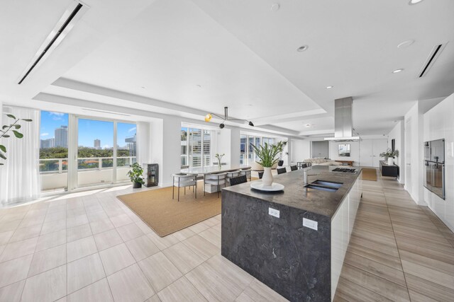 kitchen with island range hood, ceiling fan, sink, a large island, and light tile patterned flooring