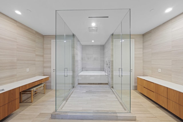 bathroom with shower with separate bathtub, vanity, and tile walls