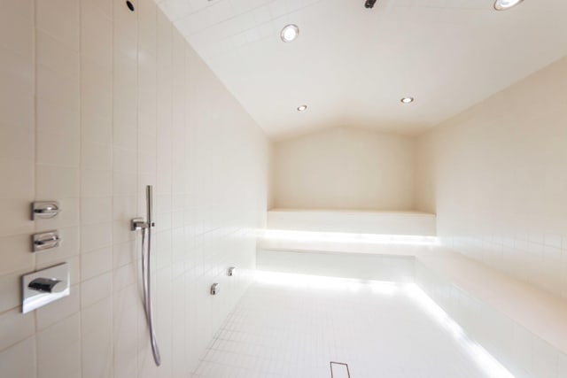 bathroom with tile patterned floors, a tile shower, and vaulted ceiling