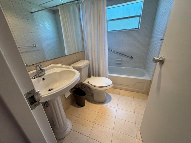 full bathroom featuring tile patterned floors, toilet, shower / tub combo with curtain, and sink