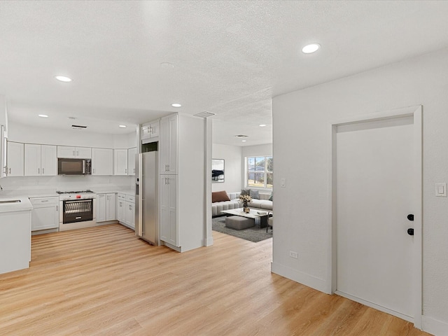 kitchen with light wood-type flooring, white cabinetry, and stainless steel appliances