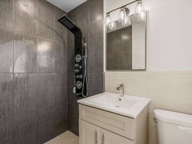 bathroom with a shower, vanity, toilet, and tile walls