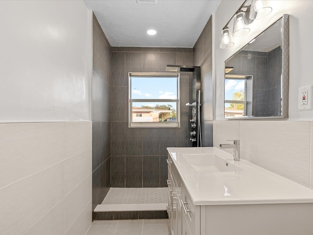 bathroom with tile patterned flooring, vanity, a shower, and tile walls