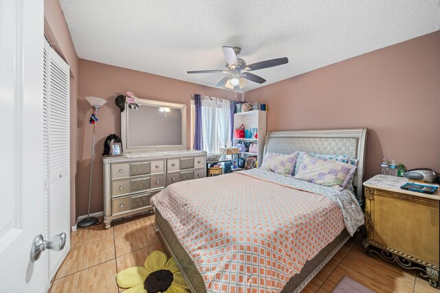 tiled bedroom with a textured ceiling, ceiling fan, and a closet