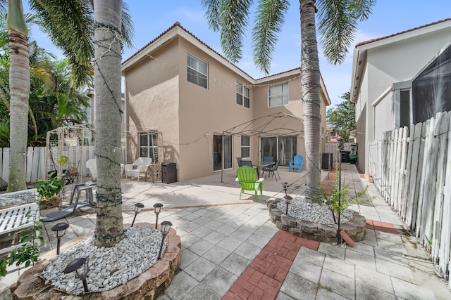 back of house with central air condition unit, a fire pit, and a patio area