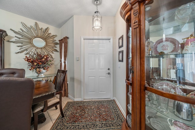 entryway with a notable chandelier, a textured ceiling, and light tile patterned floors