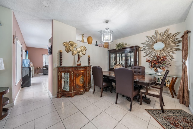 dining area featuring a textured ceiling, light tile patterned floors, and a notable chandelier