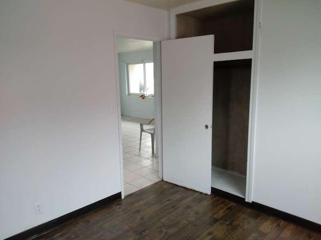 unfurnished bedroom featuring dark wood-type flooring and a closet