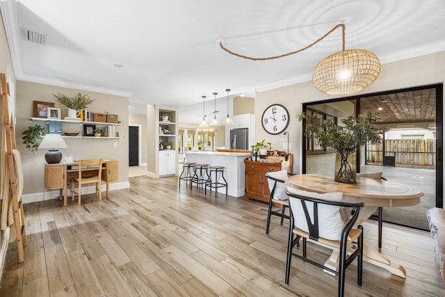 dining room featuring crown molding and light hardwood / wood-style flooring