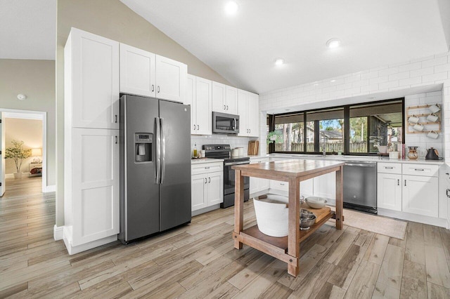 kitchen featuring white cabinets, appliances with stainless steel finishes, light wood-type flooring, and lofted ceiling