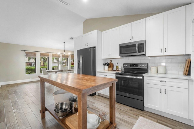 kitchen with white cabinets, light wood-type flooring, stainless steel appliances, and vaulted ceiling