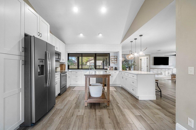 kitchen featuring white cabinetry, light hardwood / wood-style flooring, decorative light fixtures, a breakfast bar, and appliances with stainless steel finishes