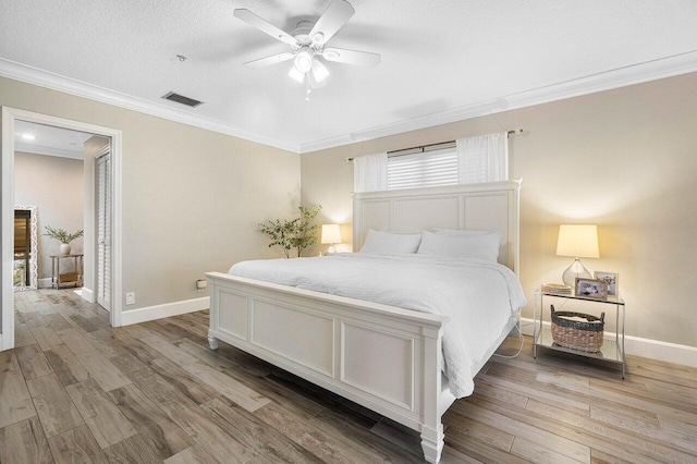 bedroom featuring ceiling fan, light hardwood / wood-style floors, ornamental molding, and a textured ceiling