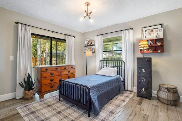 bedroom featuring a chandelier, wood-type flooring, a textured ceiling, and multiple windows